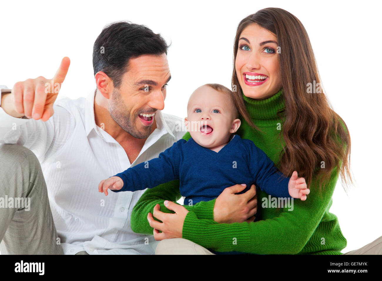 A photo of happy parents playing with son. Father pointing away while looking at baby boy. They are in casuals isolated Stock Photo