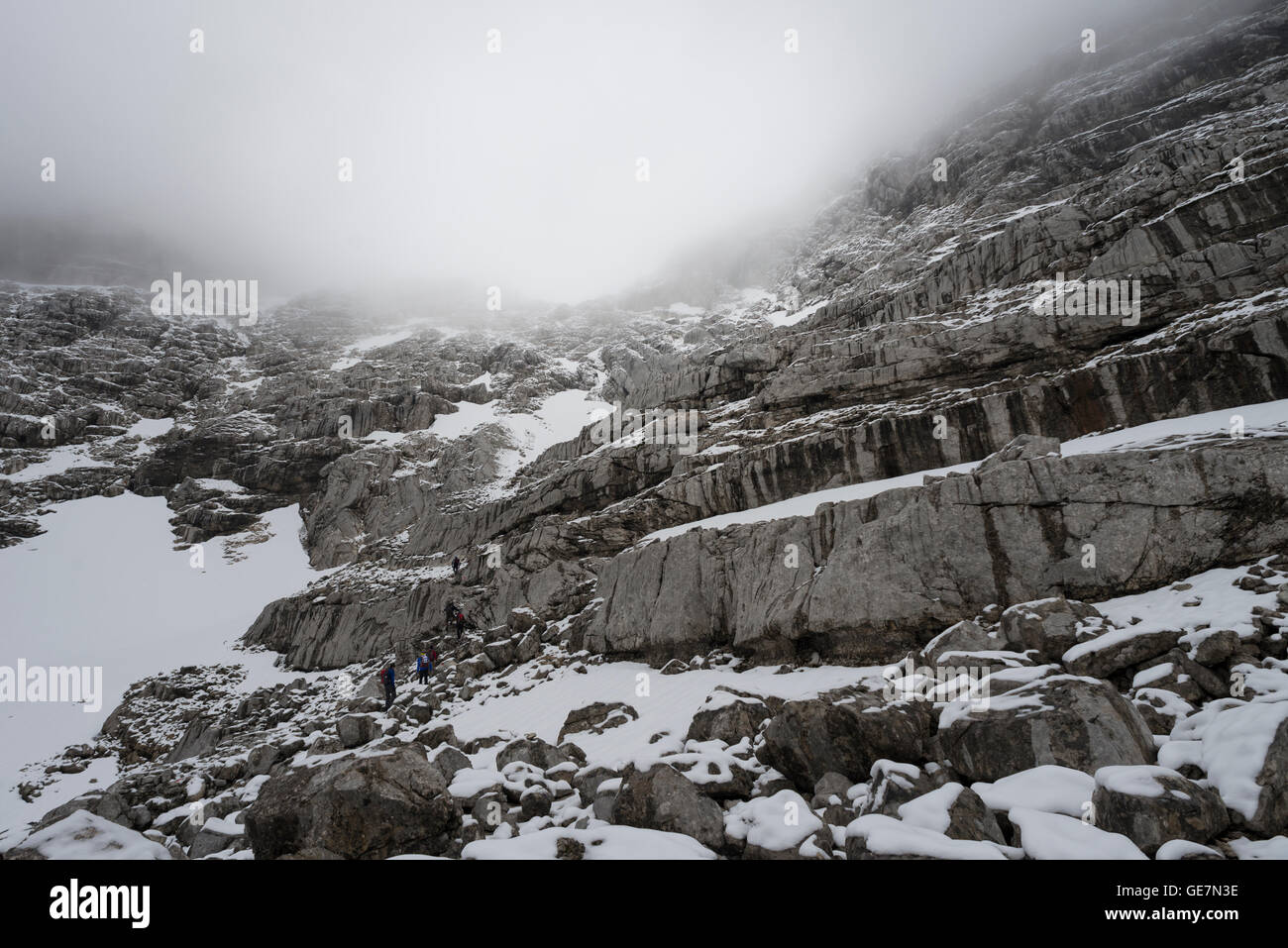 Ascend through mist and snow covered rock ledges to the Wehrgrubenjoch saddle in the Lofer Mountains, Salzburg, Austria Stock Photo