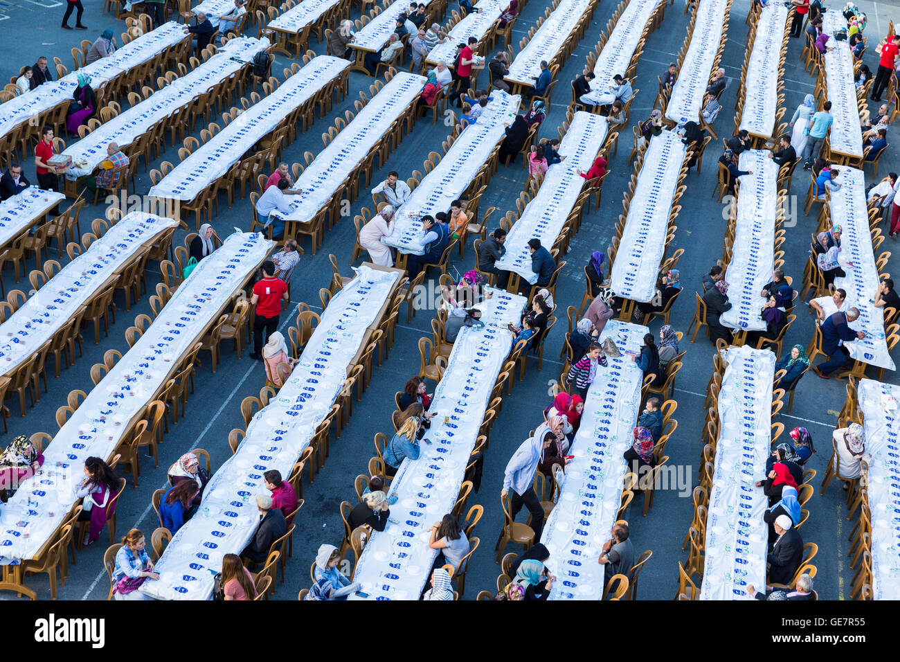 Rows of tables set up for Ramadan and crowd of people waiting the Iftar food Stock Photo