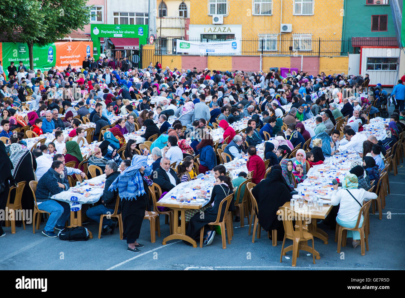 Rows of tables set up for Ramadan and people waiting the Iftar food Stock Photo