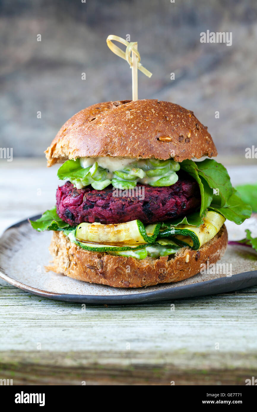 Vegetarian beetroot and black beans burger with grilled courgettes and broad beans Stock Photo