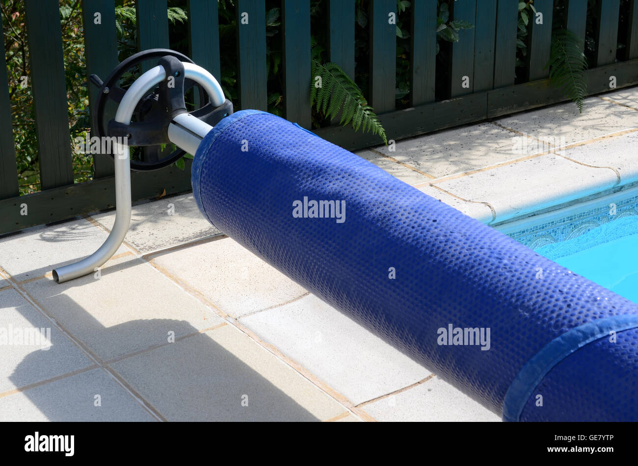 Swimming pool cover on its roller at the end of the pool Stock Photo