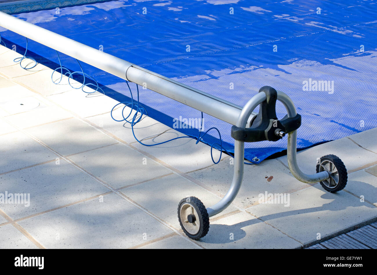 Swimming pool cover off its roller and covering the pool Stock Photo