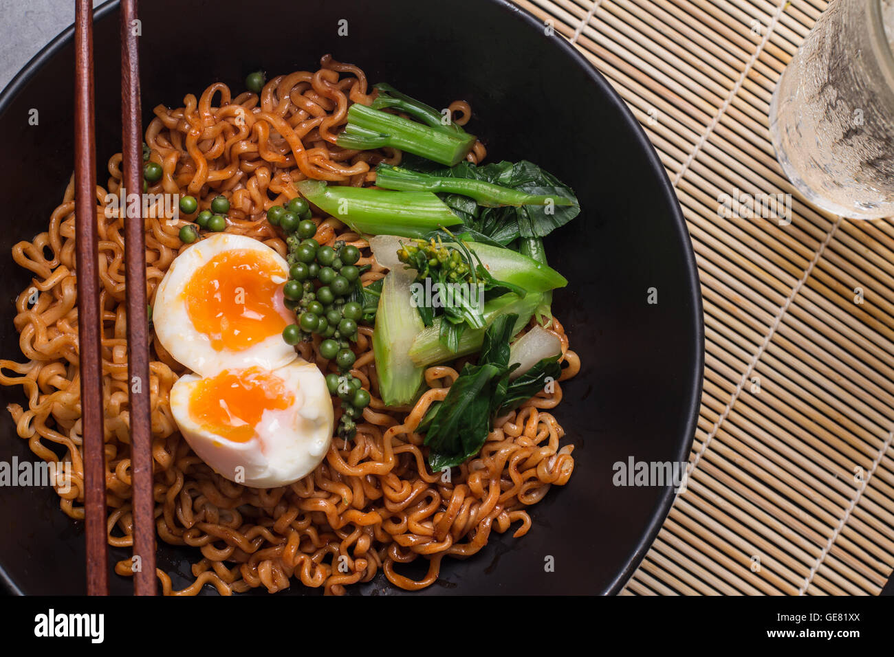 noodles in black bowl garnished on kitchen table Stock Photo