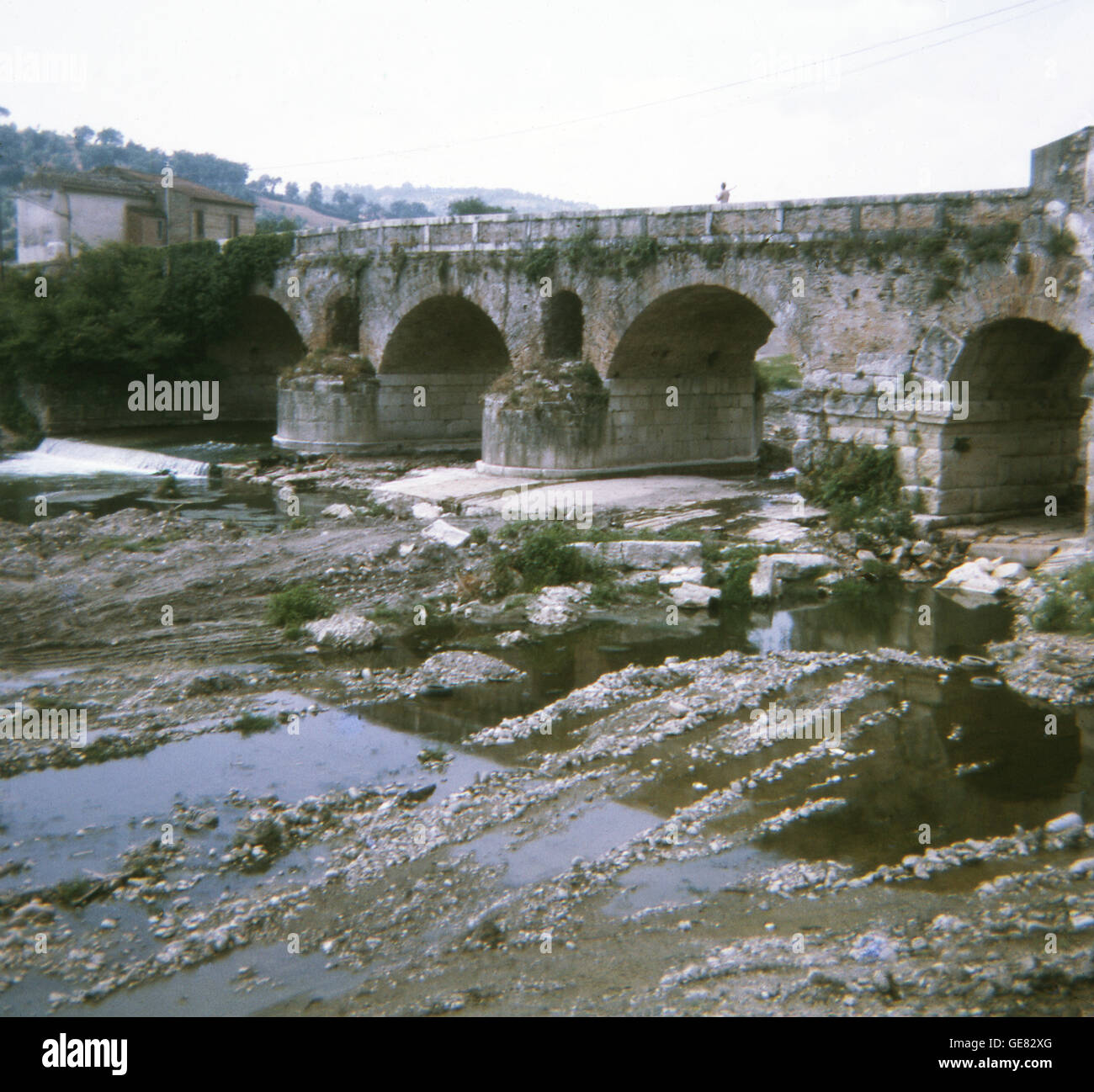 This bridge at Benevento (ancient Beneventum)  in southern Italy, in the region known as Campania, still has a bridge, known as Ponte Leproso, that is used today and dates to Roman times. The openings higher up in the bridge construction allow for extra water to flow through in times of flooding. The bridge was on the famed and well-used Via Appia (Appian Way) that led from Brindisi (ancient Brundisium) to Rome. The bridge crosses th Sabato River and is considered a marvel of Roman engineering and ingenuity. This photo was taken in the summer of 1970. Stock Photo
