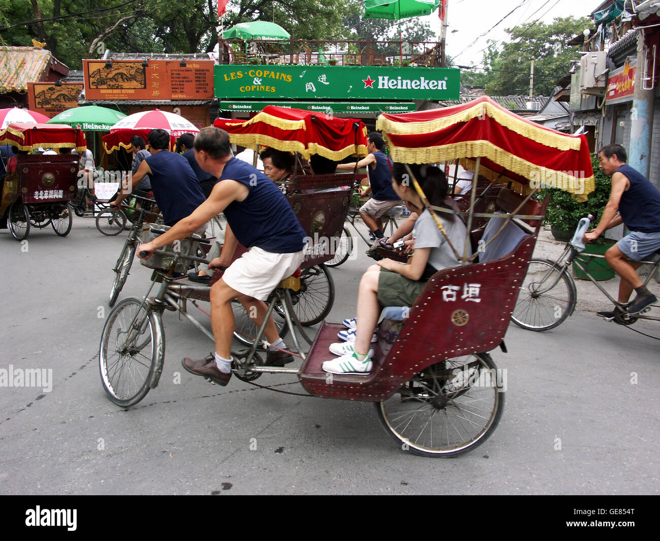 Bicycle rickshaw taking tourists through a hutong neighborhood. Beijing ...