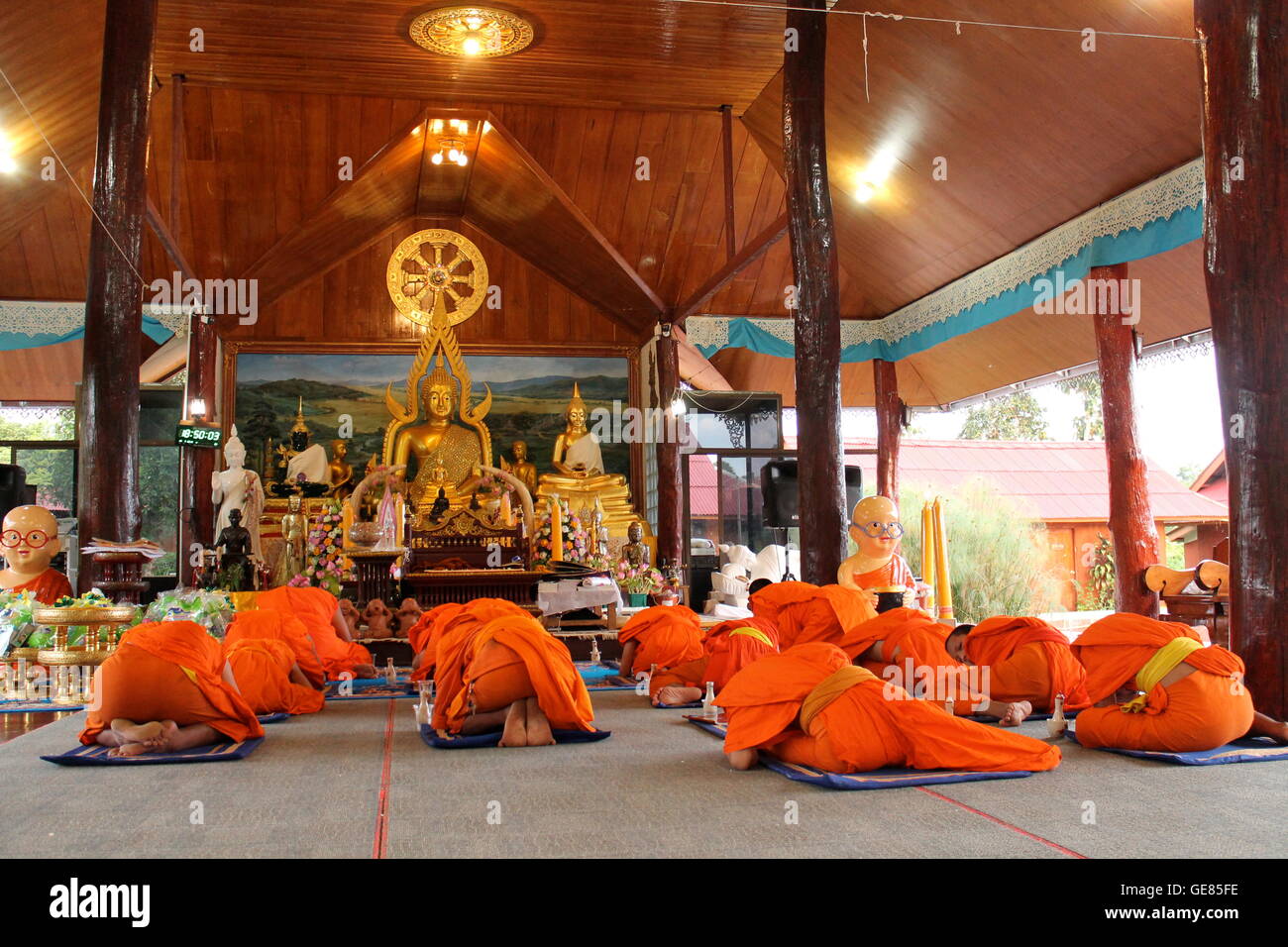 Thai Buddhist monks and novices prostrating during evening chanting ceremony Wiang Haeng Stock Photo