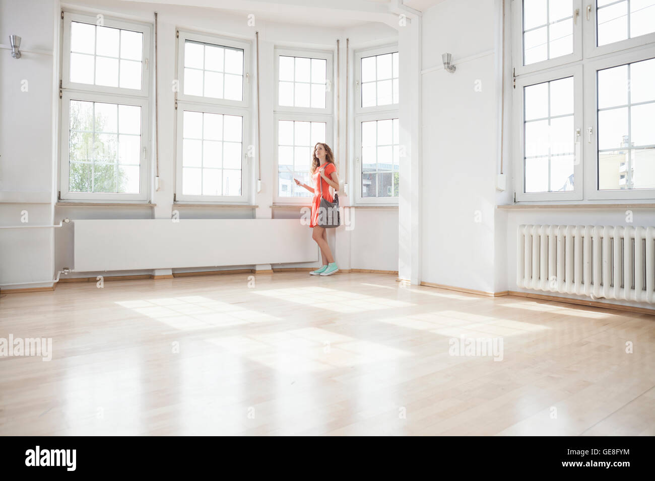 Woman looking around in empty apartment Stock Photo