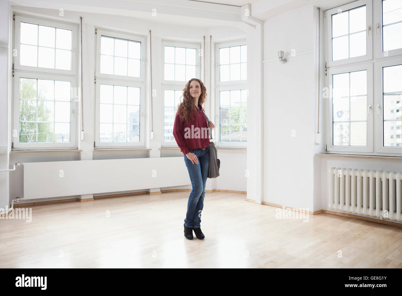 Woman looking around in empty apartment Stock Photo