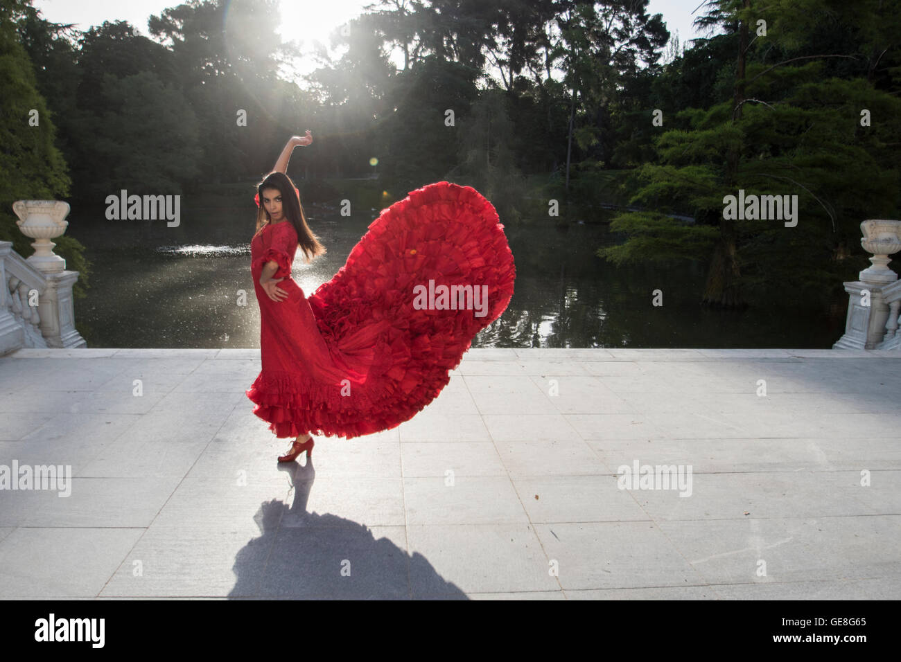 Woman dressed in red dancing flamenco on a terrace in front of a lake Stock Photo