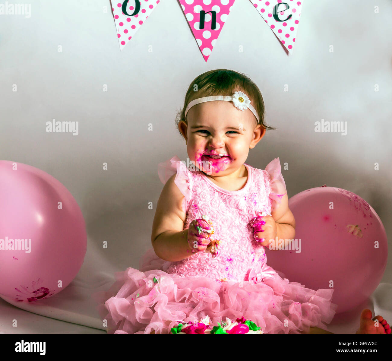 A laughing one year old eating cake and covered in icing Stock Photo ...