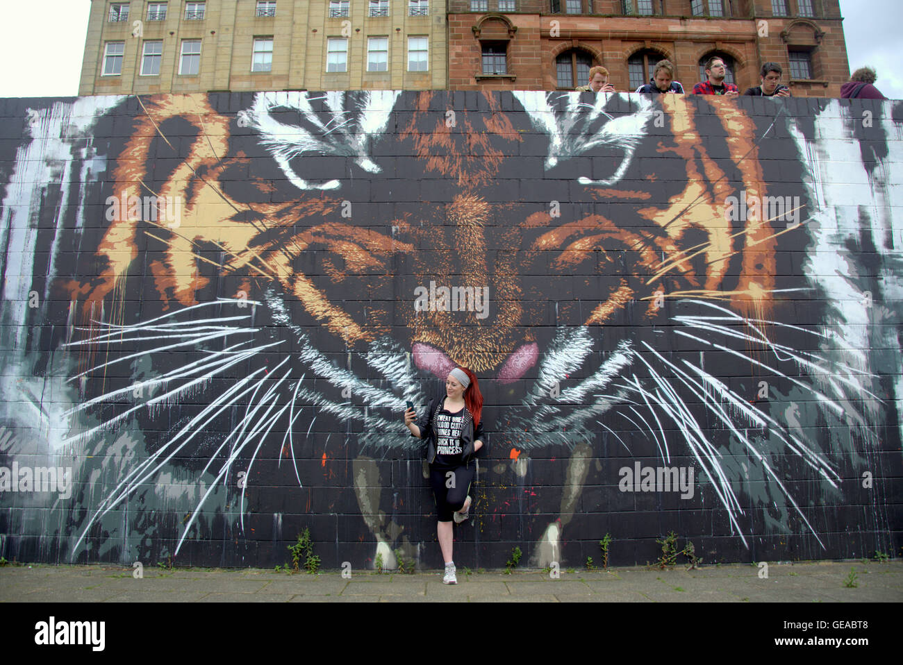 Glasgow, Scotland, UK 23rd July 2016. The Tiger mural on the River Clyde finds itself at the centre of the Pokémon phenome. The artwork by local Artist Art Pistol has found itself at the centre of the city’s Poke Stop Glasgow’s newest social hub for gamers of all ages. Attracting a wide gamut of people to the Riverside the strange sight of a large crowd individually contemplating their phones is proving one of the city’s latest attractions. Credit: Gerard Ferry/Alamy Live News Stock Photo
