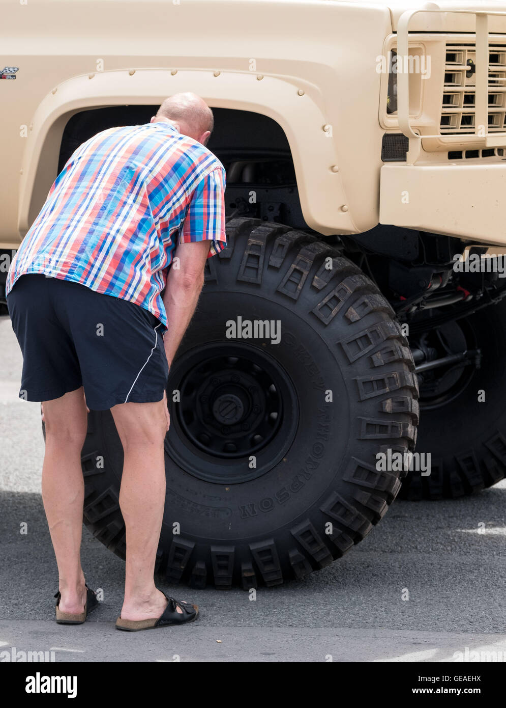 An overszed tyre of a Pick-up truck is being tended to by a man at the 'Street Mag Show' in Hanover, Germany, 24 July 2016. On 23 and 24 July, many classics of American automotive history will be shown on the Schuetzenplatz in Hannover at the 'Street Mag Show'. Photo: PETER STEFFEN/dpa Stock Photo
