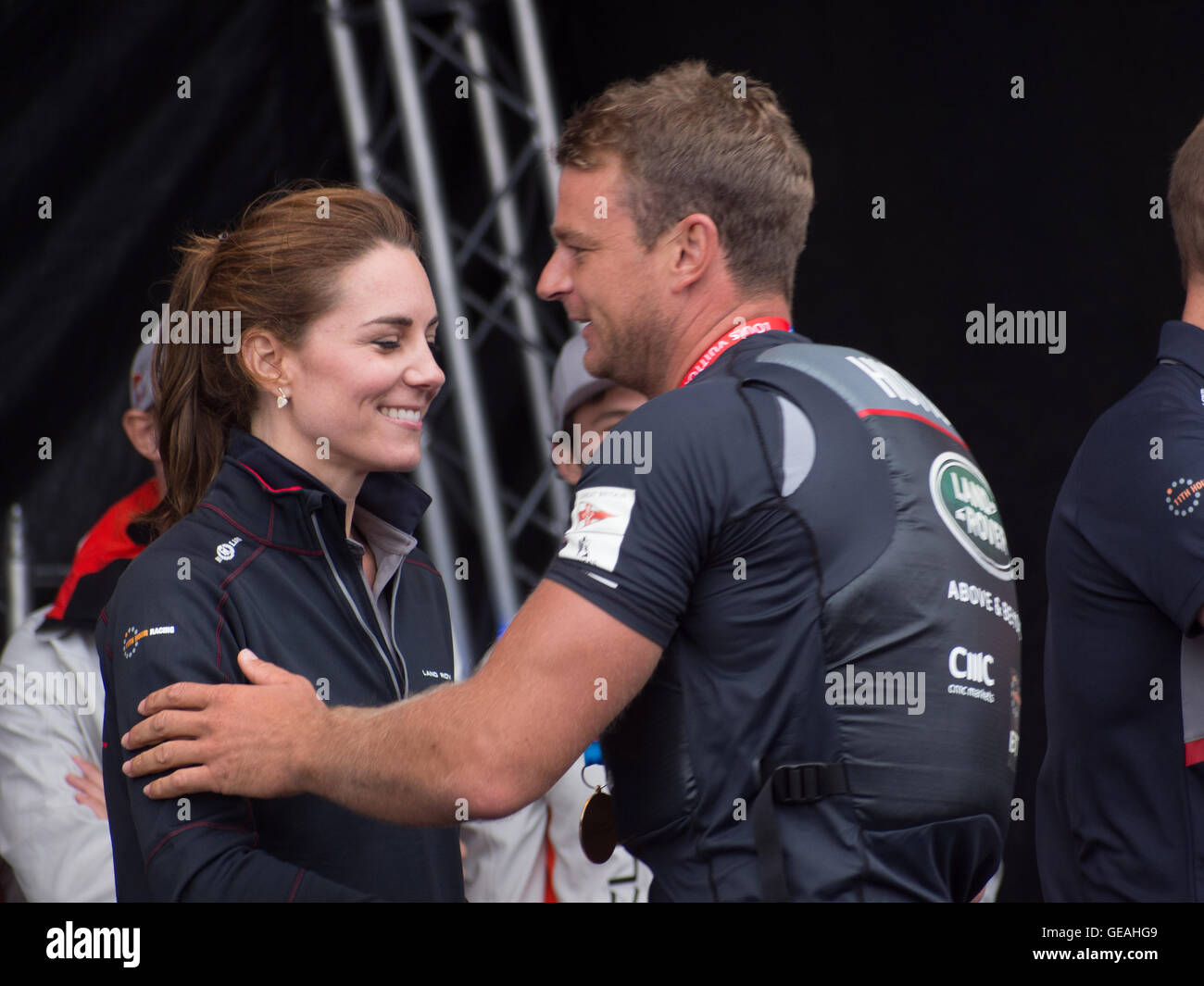 Portsmouth, UK, July 24 2016. Nick Hutton, Trimmer, with Land Rover BAR gives the Duchess of Cambridge a friendly pat on the arm as she presents him with the winners trophy at The Americas Cup World Series in Portsmouth. Credit:  simon evans/Alamy Live News Stock Photo