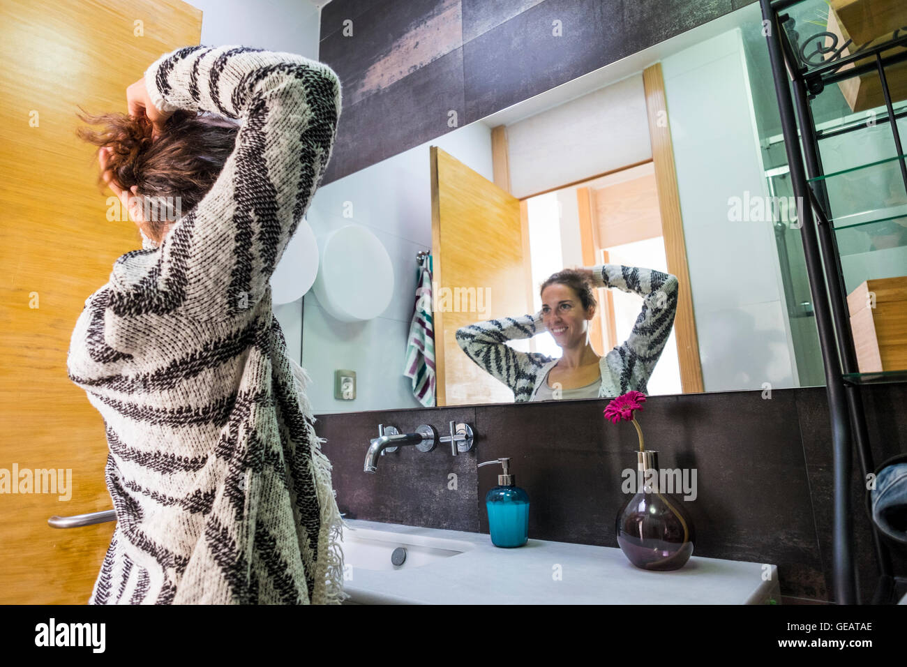 Young woman at home doing her hair in front of mirror Stock Photo - Alamy
