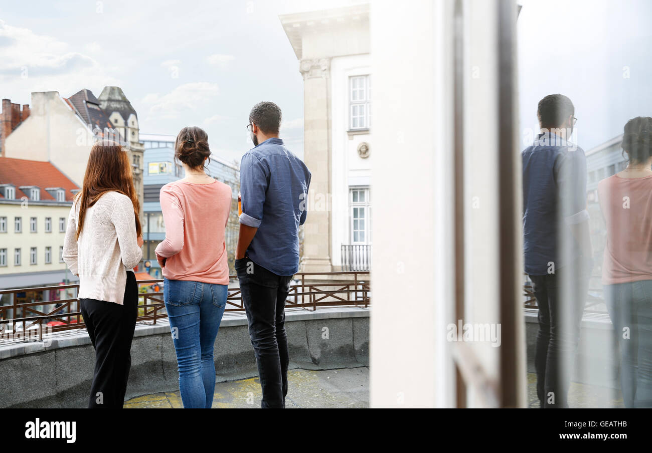 Man and two women standing on roof terrace Stock Photo - Alamy