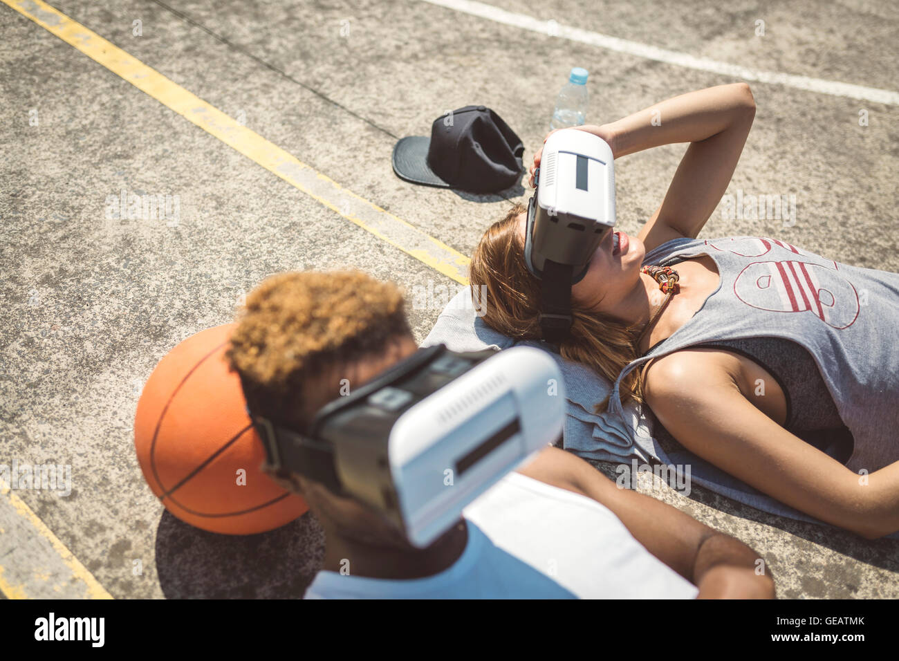Young couple using virtual reality glasses, resting heads on basketball Stock Photo