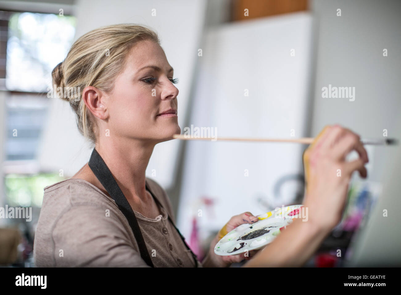 Woman in her home studio, painting, holding palette in her hand Stock ...