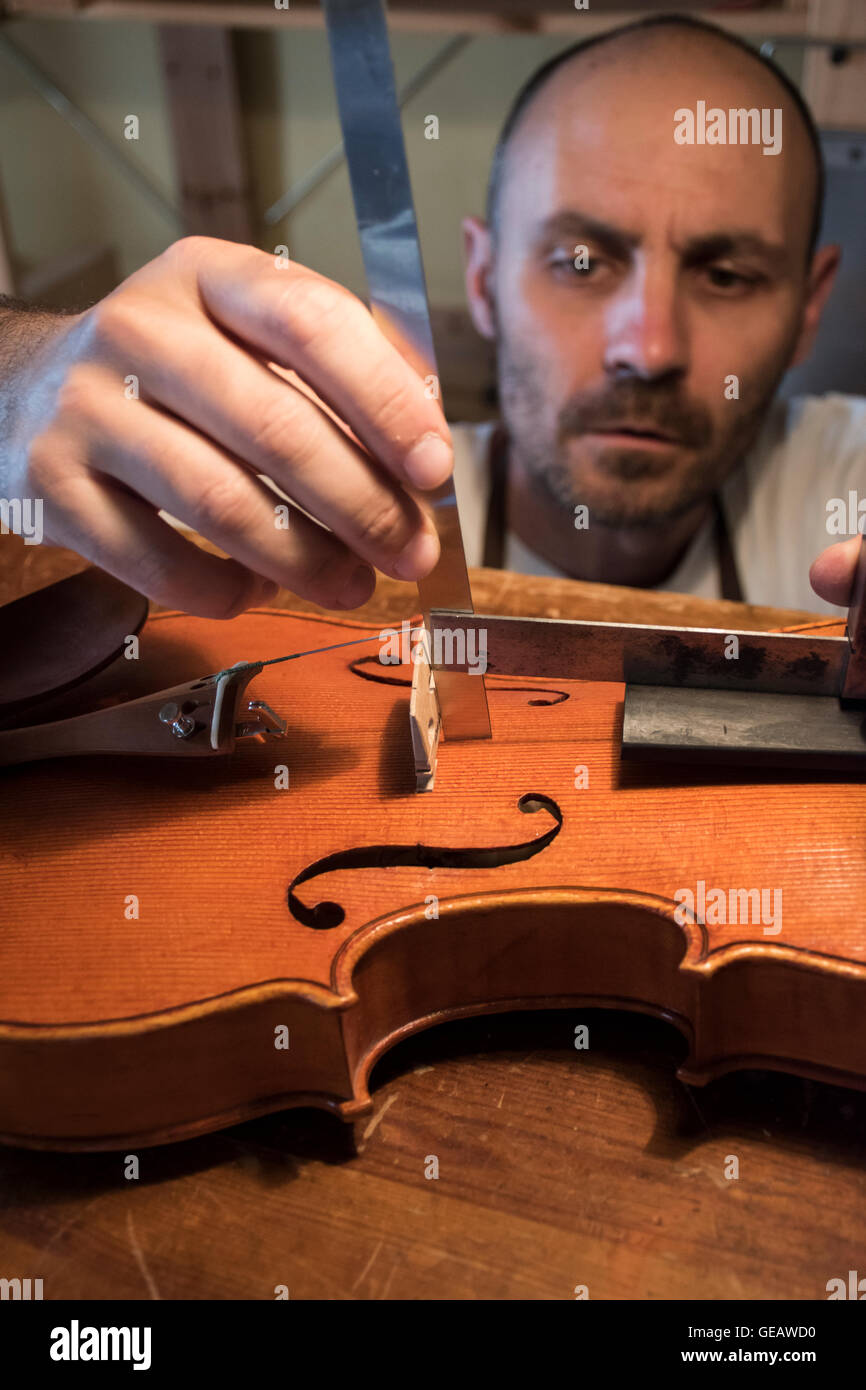 Luthier making measurements during the manufacture of a violin in his
