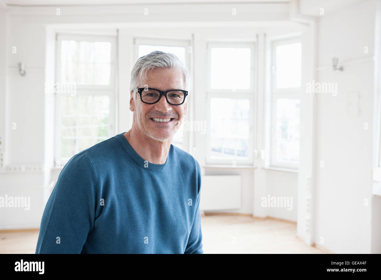 Portrait of smiling man in empty apartment Stock Photo