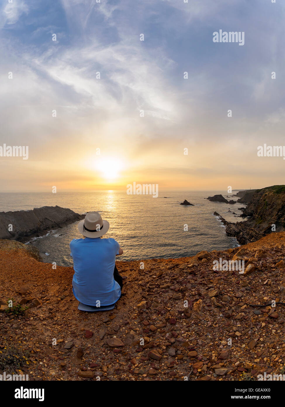 Portugal, Senior man sitting at bay watching sunset Stock Photo