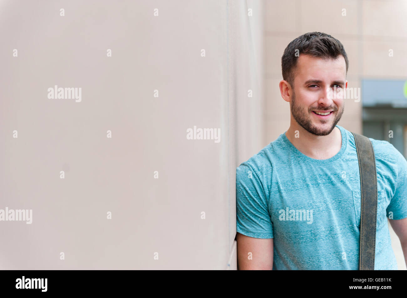 Portrait of smiling young man leaning against a wall Stock Photo - Alamy
