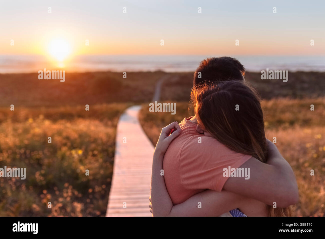 Romantic young couple embracing on the beach at sunset Stock Photo - Alamy