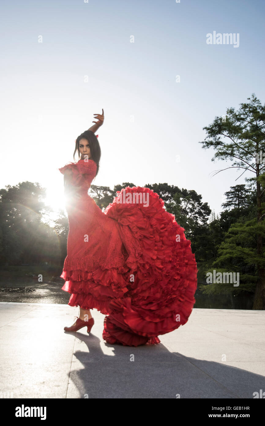 Woman dressed in red dancing flamenco on terrace at backlight Stock Photo