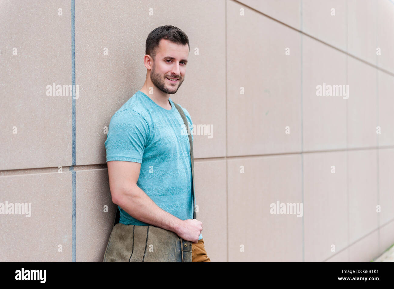 Portrait of smiling young man leaning against a wall Stock Photo - Alamy