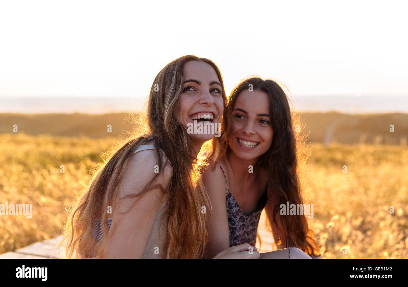 Happy young women sitting on the beach Stock Photo - Alamy