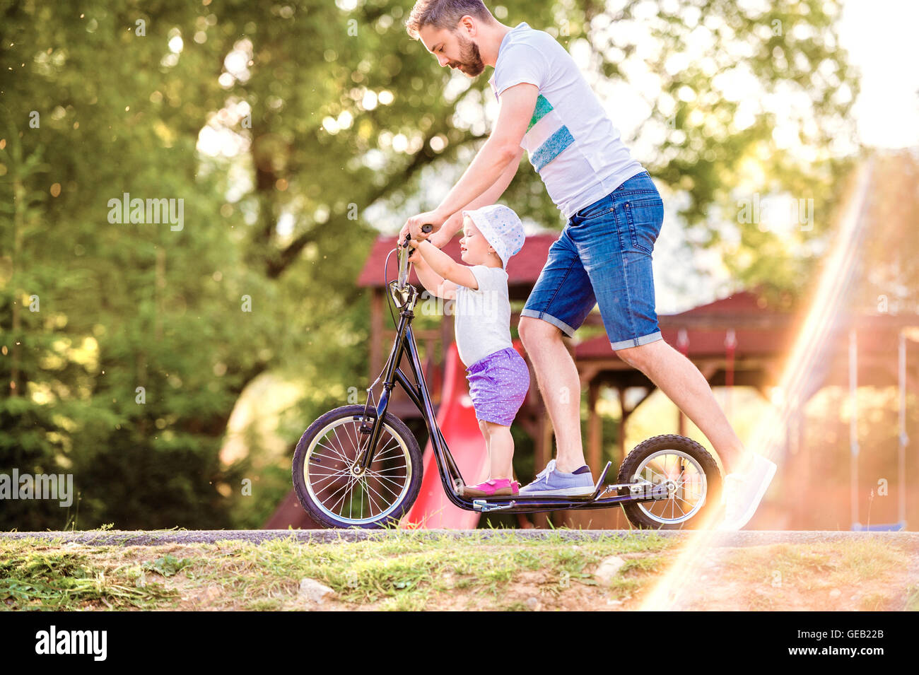 Father and little daughter together on a scooter Stock Photo