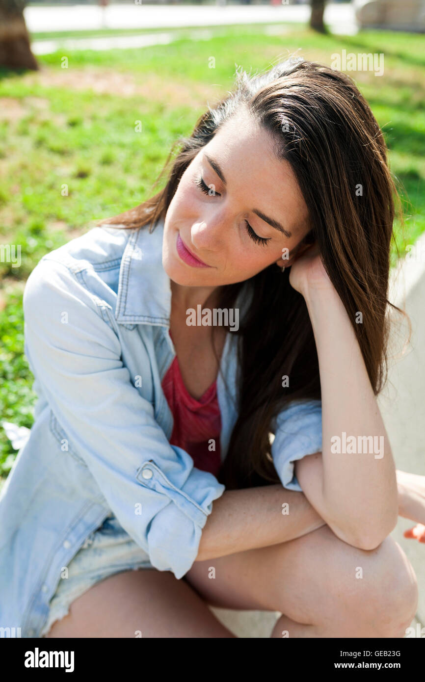 Young woman sitting park with eyes closed Stock Photo - Alamy