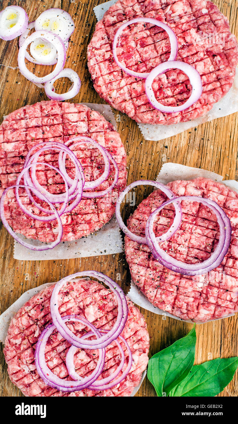 Raw ground beef meat cutlet for making burgers with onion rings and