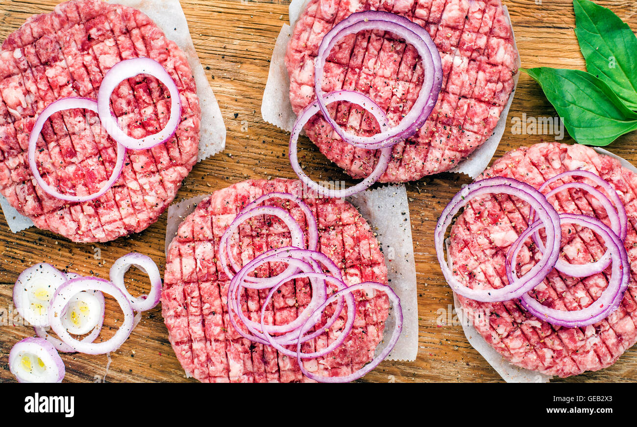 Raw ground beef meat cutlet for making burgers with onion rings and