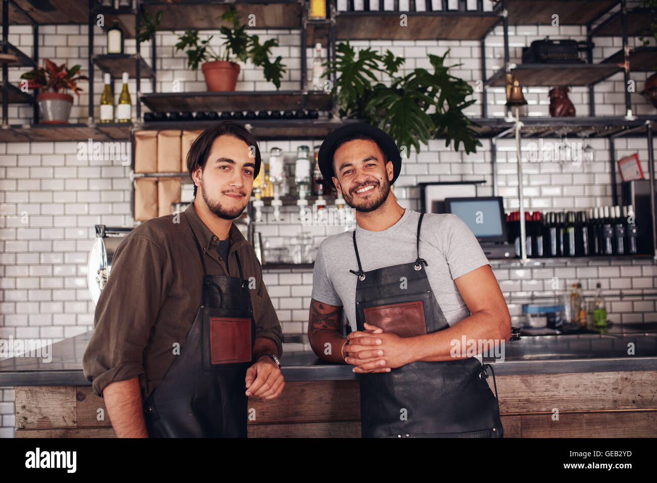 Portrait of two young coffee shop owners at the counter. Cafe partners standing together and looking at camera. Stock Photo