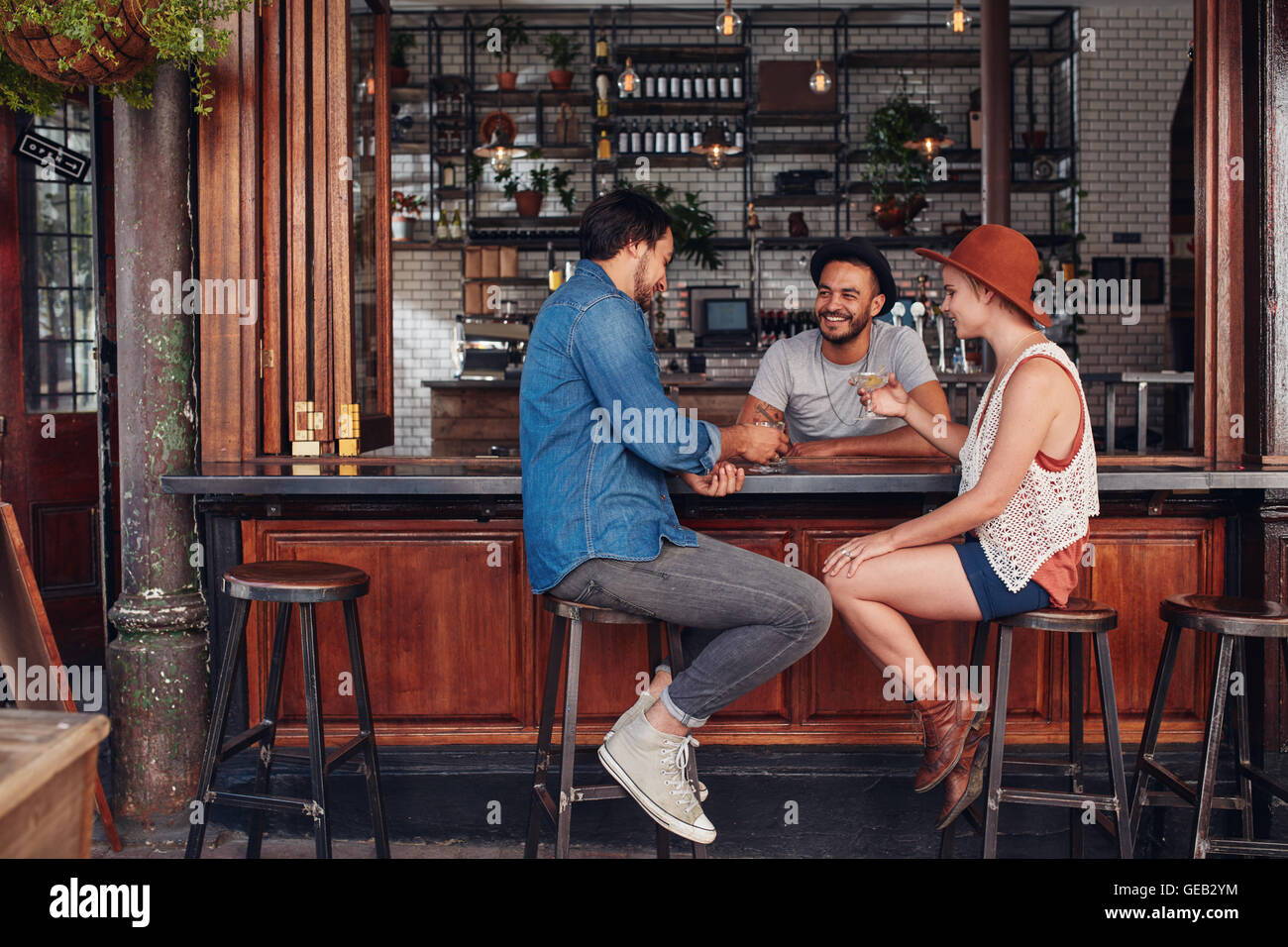 Group of young friends sitting and talking at a cafe. Young men and women meeting in a coffee shop. Stock Photo