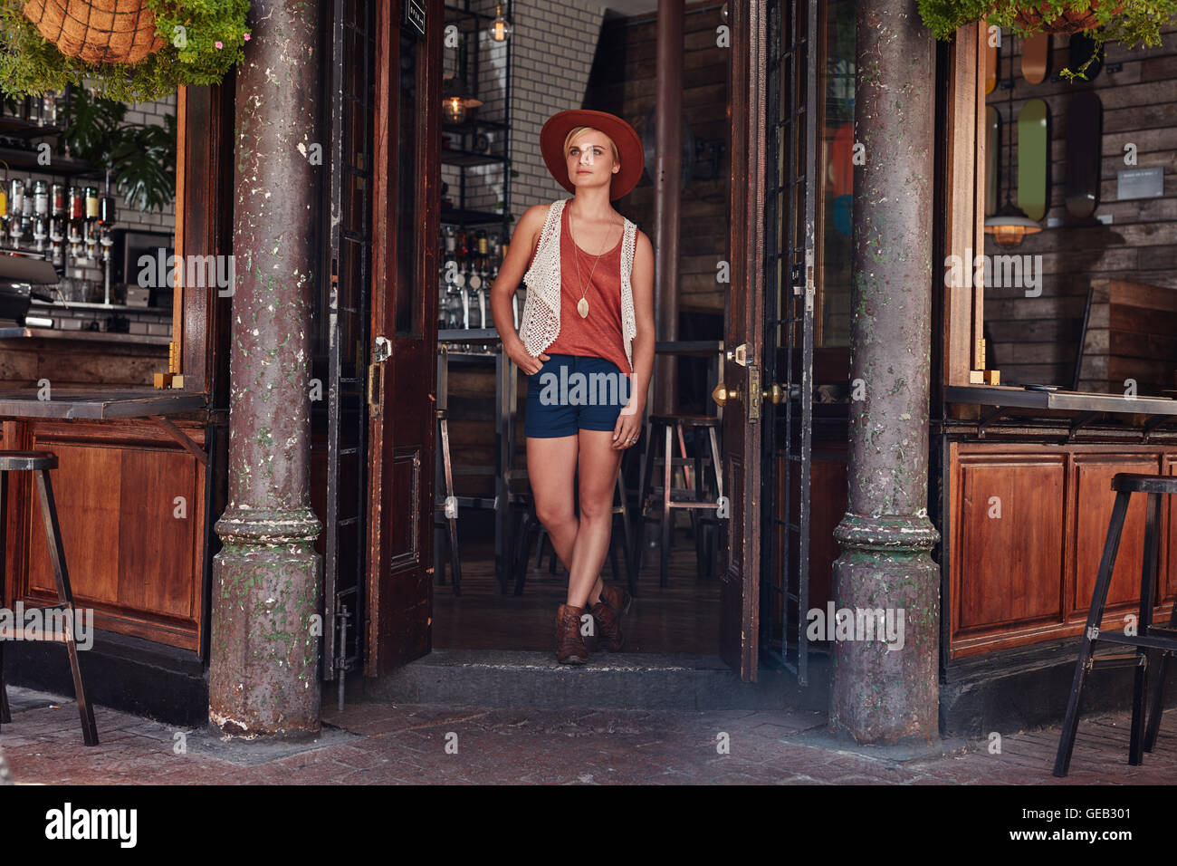 Full length portrait of trendy young woman leaving coffee shop. Stylish young woman walking out of a cafe. Stock Photo