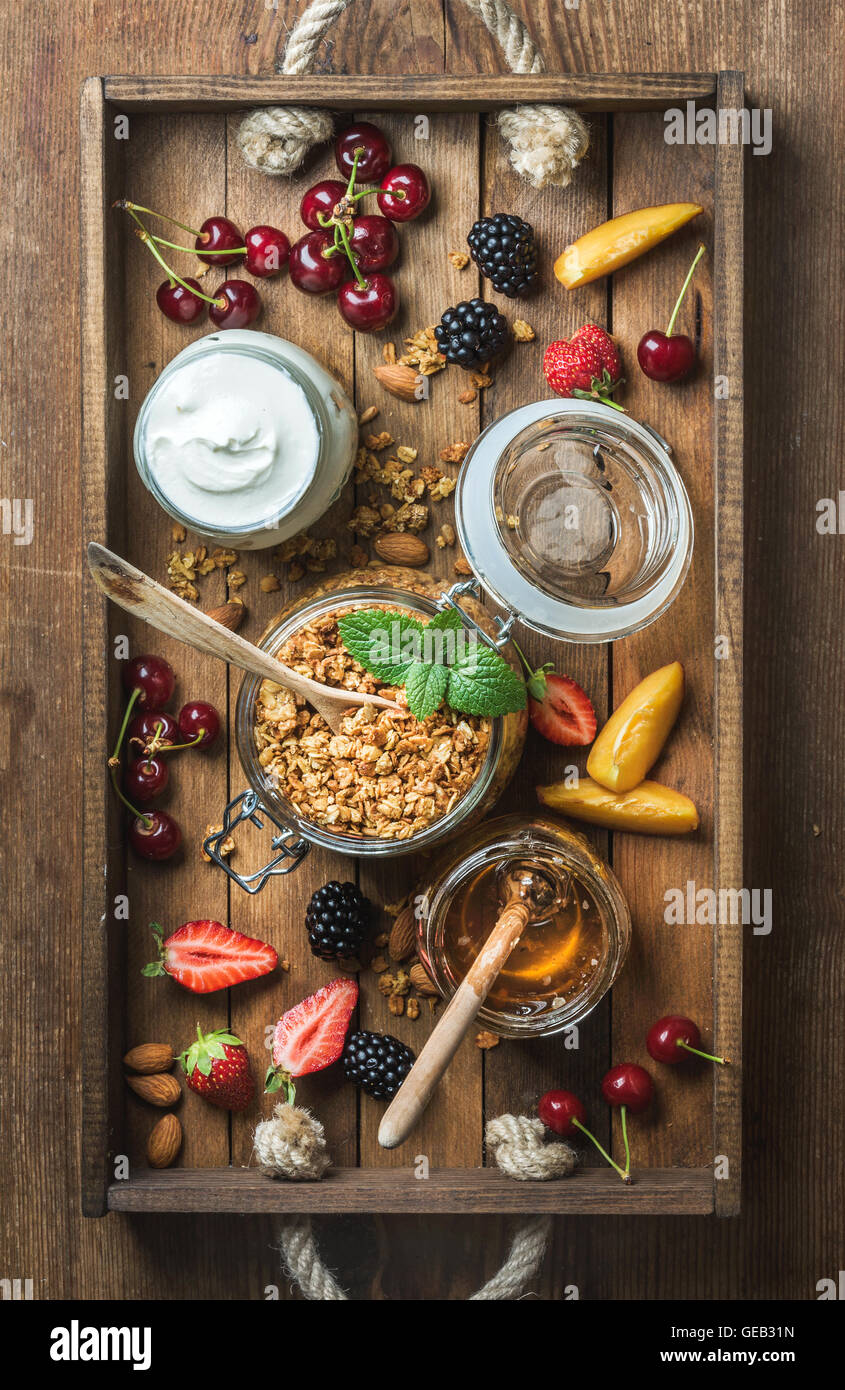 Healthy breakfast ingredients. Oat granola in open glass jar, fruit
