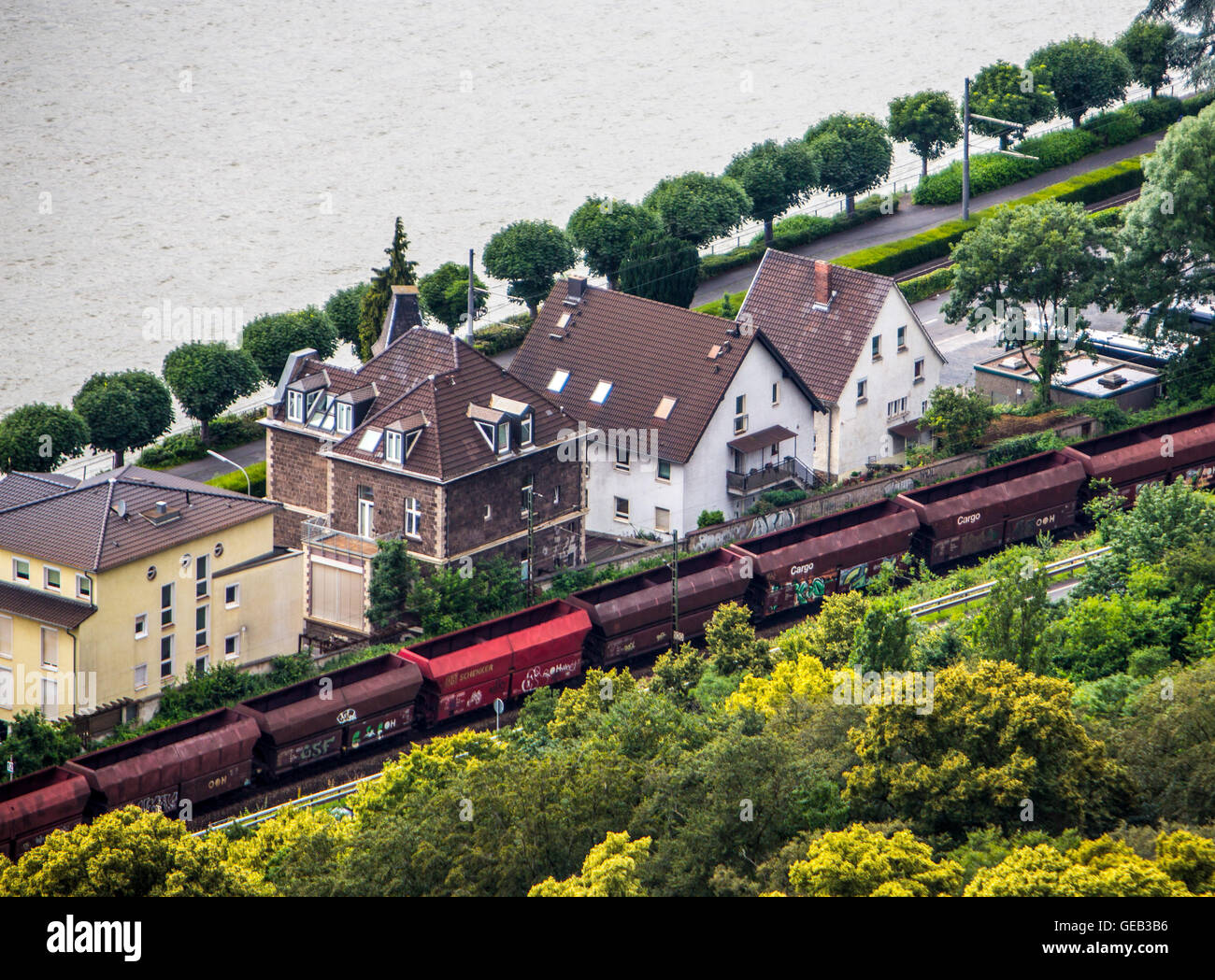 Freight train running directly next to private homes, without a noise barrier, river Rhine, Germany Stock Photo