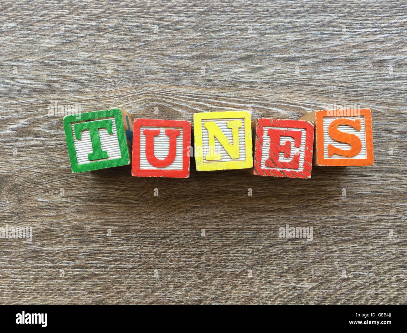 Alphabet wood block letters forming the word TUNES, combining those toys letters help kids to learn and write english Stock Photo