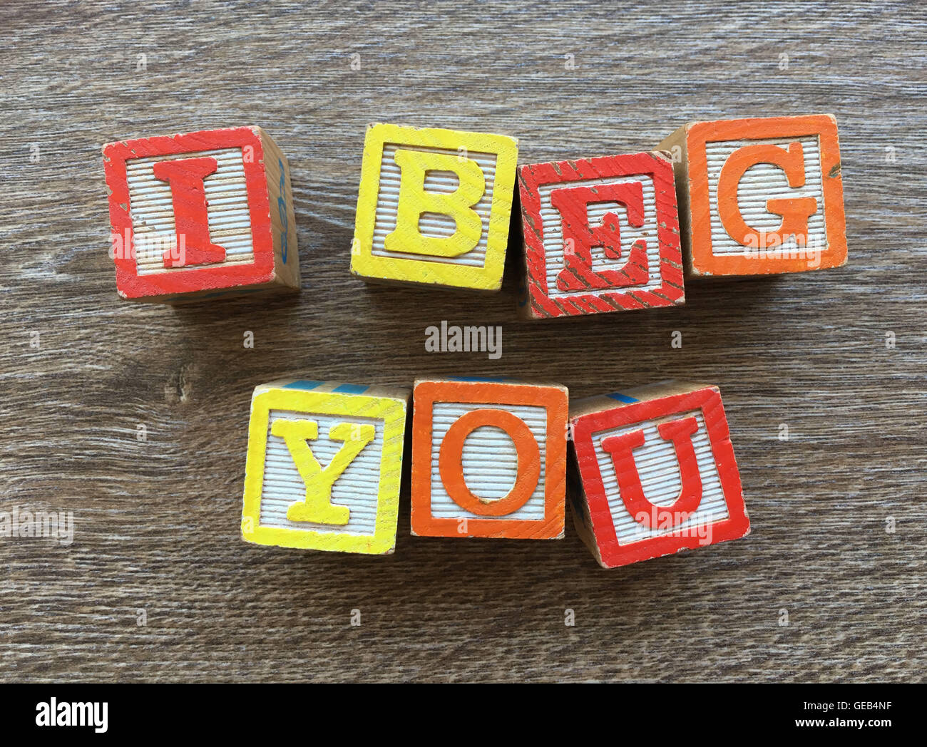 I BEG YOU sentence written with wood block letter characters Stock Photo