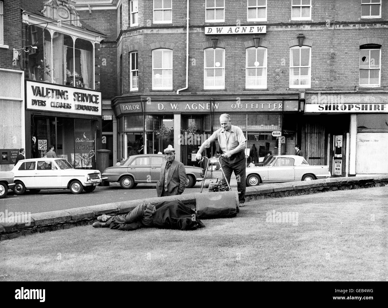 A municipal gardener has to mow the grass around a man sleeping rough Britain 1967 1960s Picture by David Bagnall Stock Photo