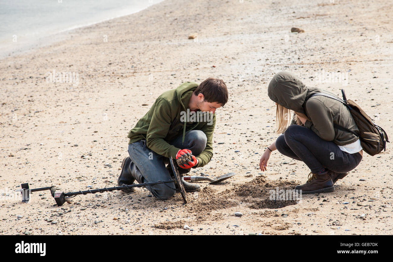 Yong man and woman Metal Detecting on the Beach in Llandudno Wales GB