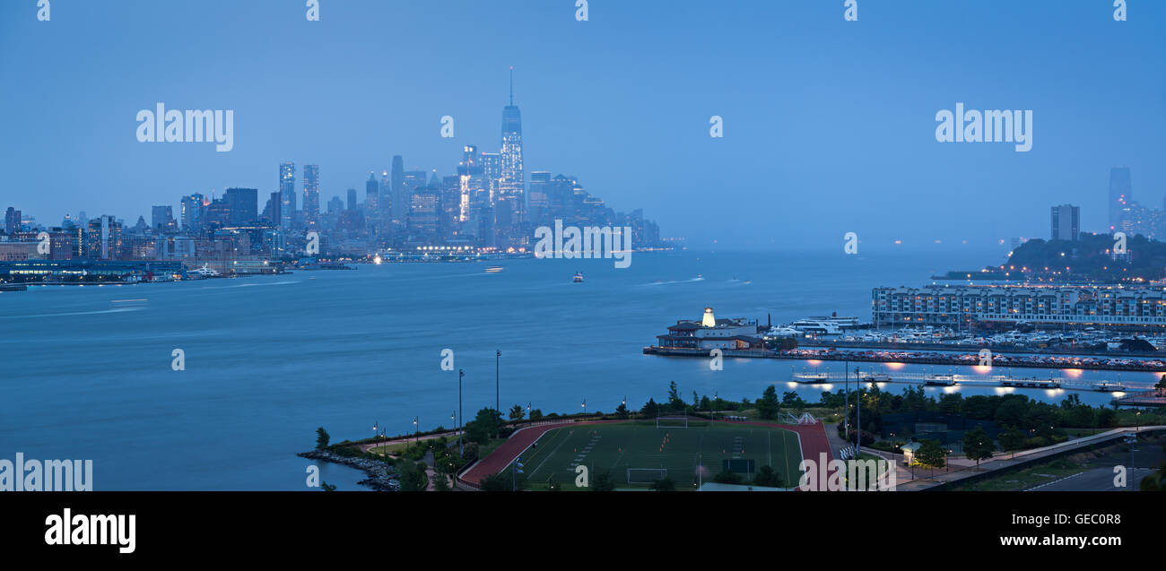 Lower Manhattan with heavy rainfall in evening and Financial District skyscrapers and Weehawken, New Jersey waterfront. New York Stock Photo
