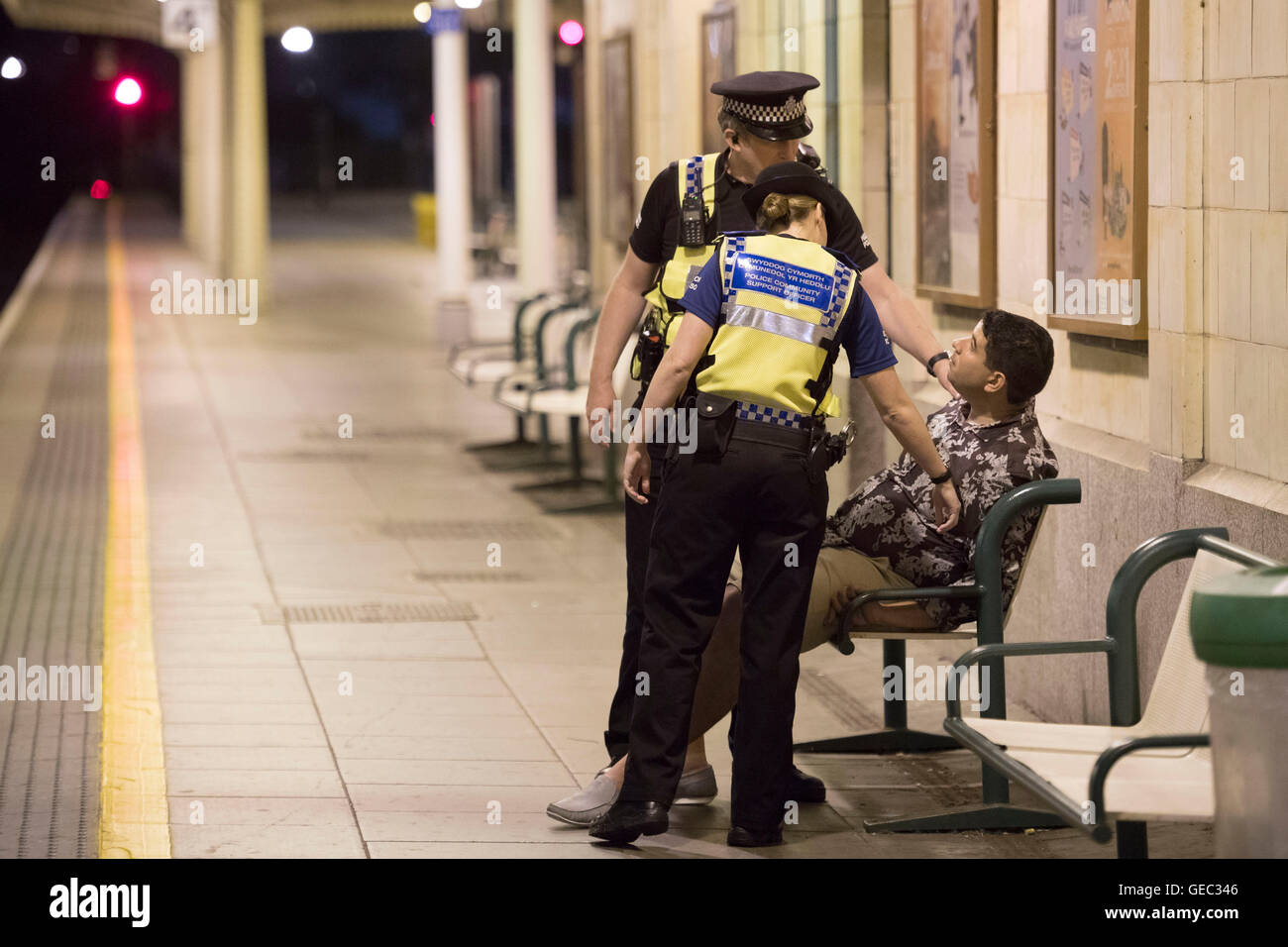 CARDIFF, WALES - JULY 22: British Transport Police help a man asleep on a bench on the platform while on patrol at Cardiff Centr Stock Photo