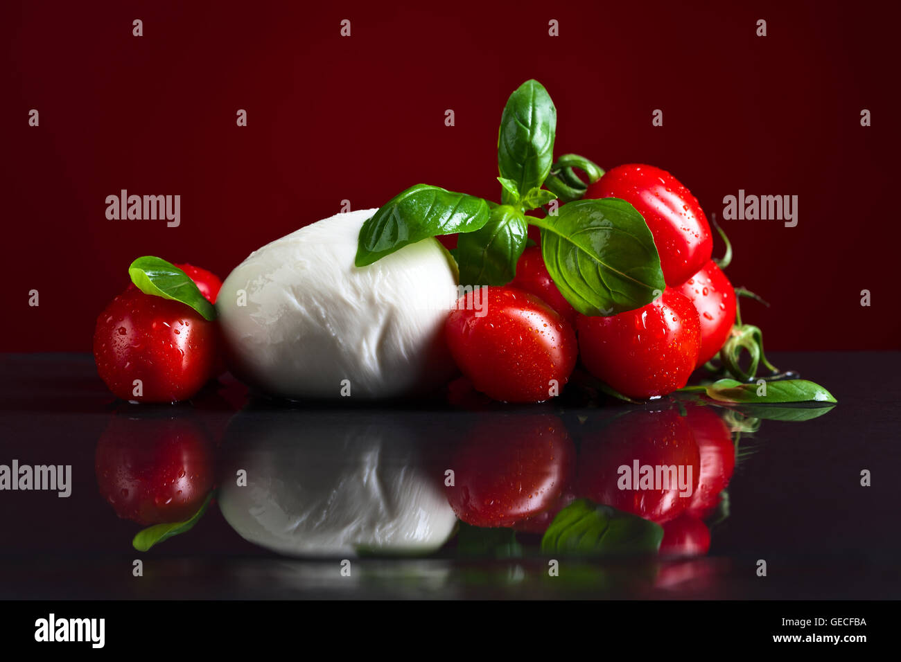 mozzarella with basil and tomatoes on black table Stock Photo - Alamy