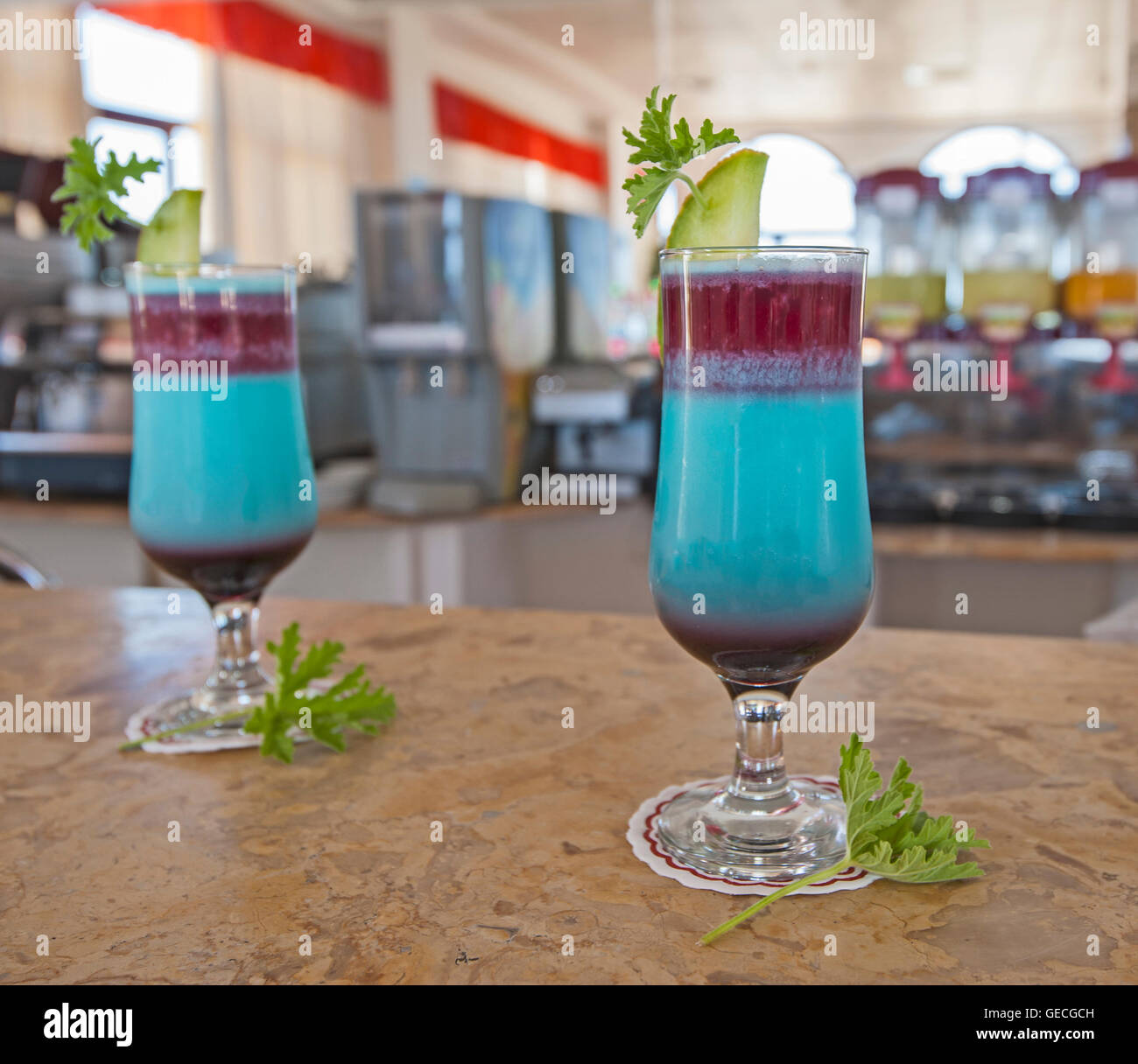 Pair of blue ornate cocktail drinks with lemon and mint on marble bar counter top Stock Photo