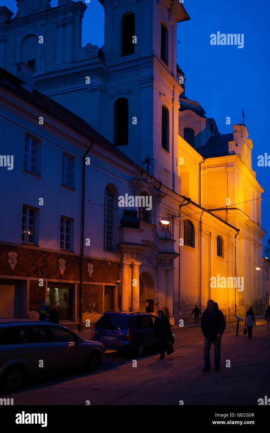 Walking down a twisting street past medieval churches and architecture at night in the Lithuanian city of Vilnius Stock Photo