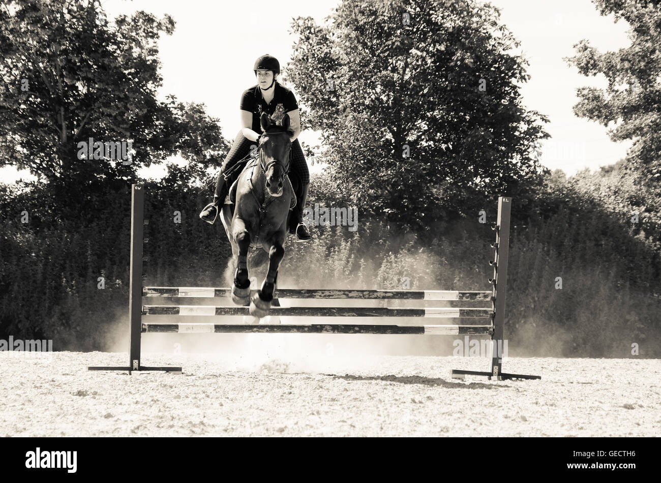 Female rider clearing an obstacle during a horse jumping practice, black-and-white Stock Photo