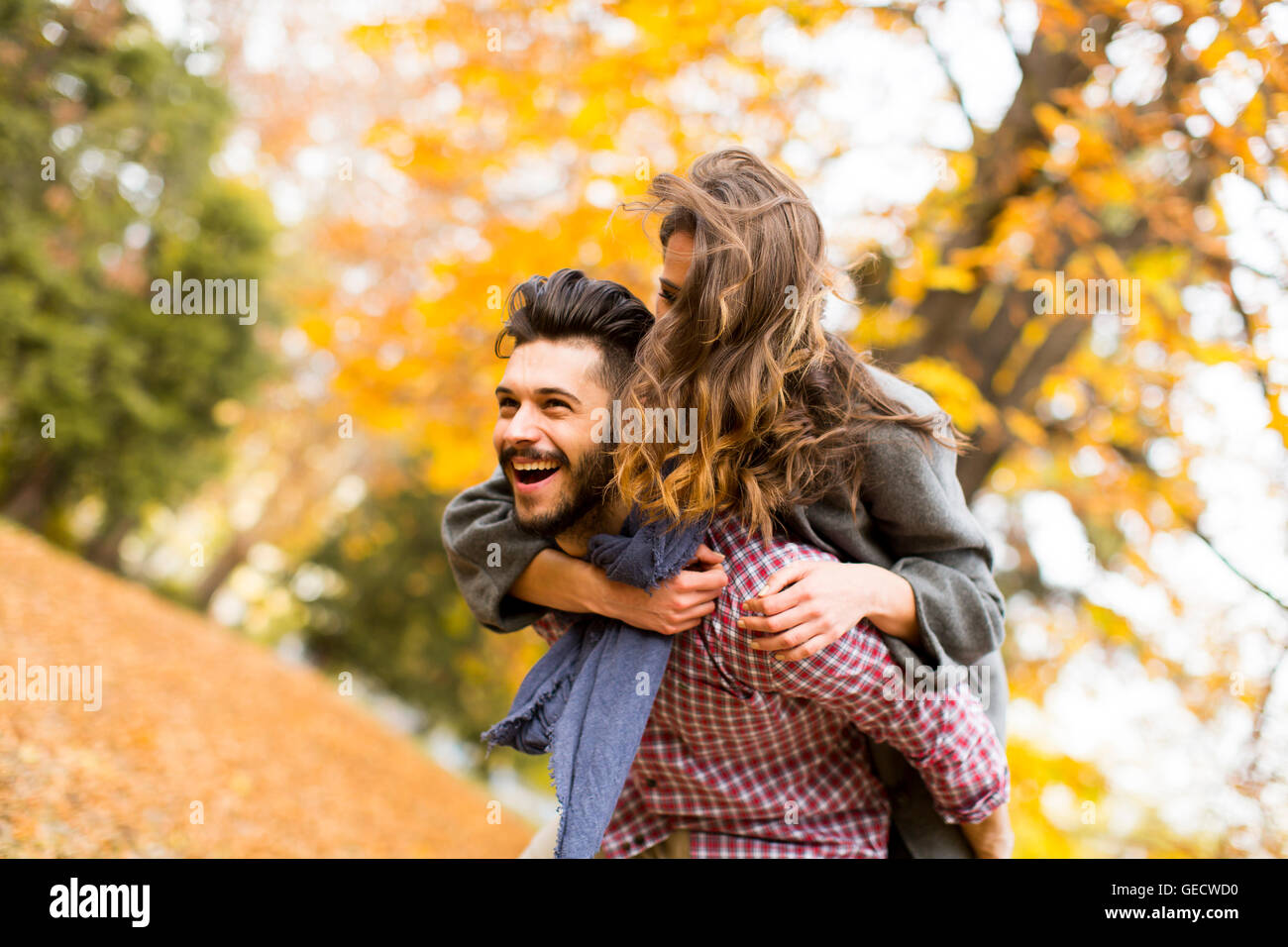 Young couple having fun in the autumn park Stock Photo - Alamy